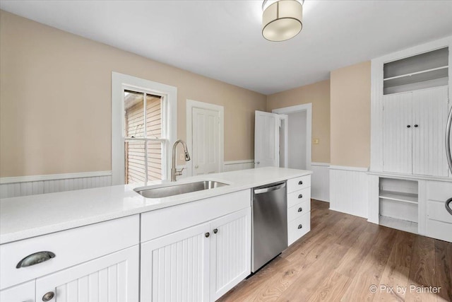 kitchen featuring white cabinetry, stainless steel dishwasher, sink, and light hardwood / wood-style flooring