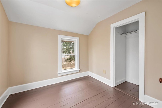 unfurnished bedroom featuring a closet, vaulted ceiling, and dark hardwood / wood-style floors