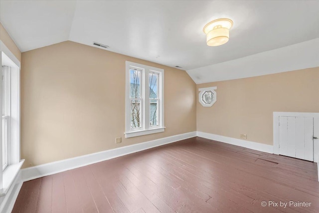 additional living space with hardwood / wood-style flooring and vaulted ceiling