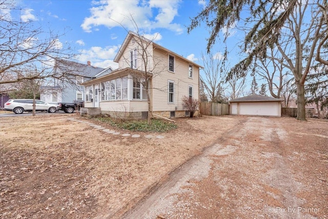 view of front of home with a garage, a sunroom, and an outbuilding