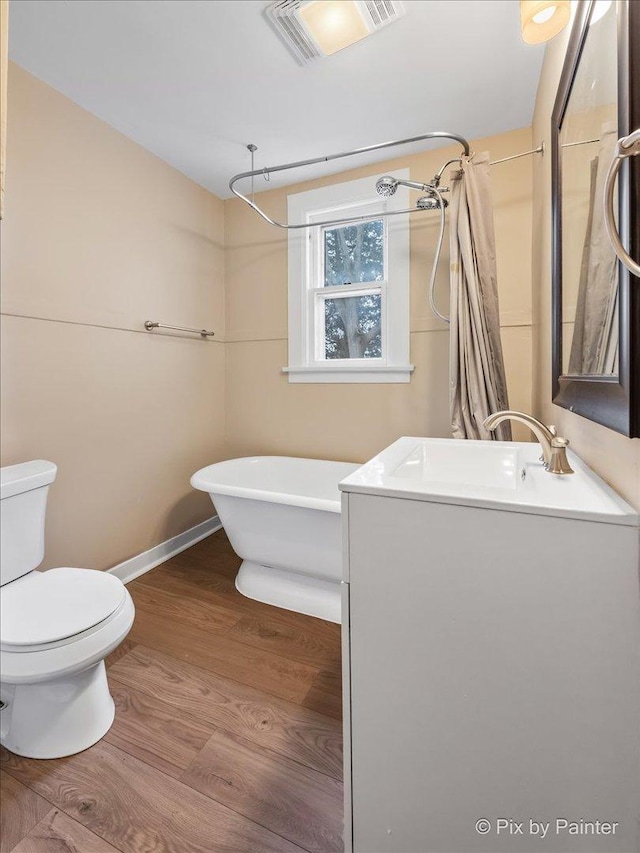 bathroom with vanity, a bath, wood-type flooring, and toilet