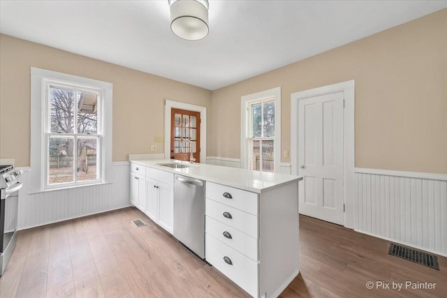 kitchen featuring sink, appliances with stainless steel finishes, white cabinetry, plenty of natural light, and kitchen peninsula