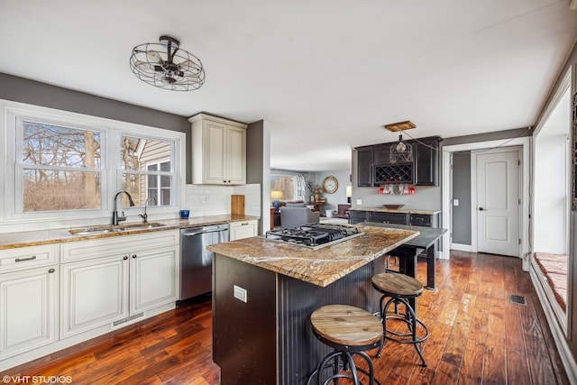 kitchen featuring visible vents, a healthy amount of sunlight, light stone countertops, stainless steel appliances, and a sink