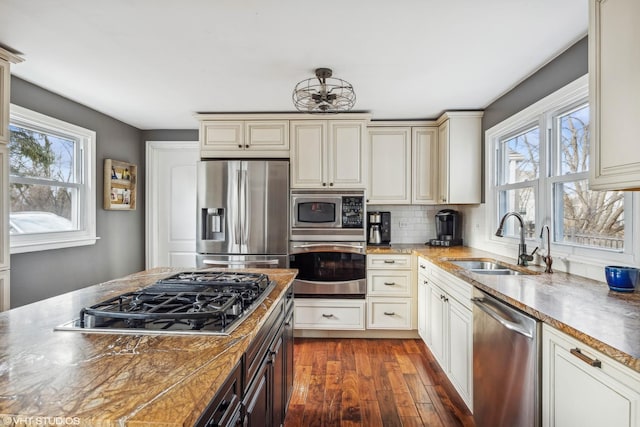 kitchen featuring dark wood-style flooring, cream cabinets, stainless steel appliances, and a sink