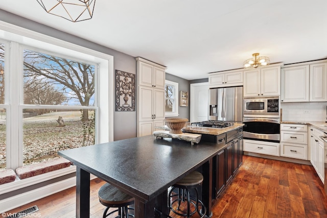 kitchen with stainless steel appliances, dark wood-type flooring, a healthy amount of sunlight, and visible vents