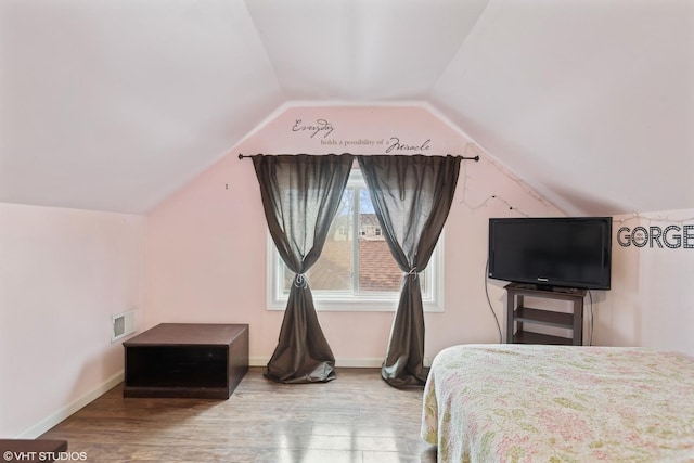 bedroom featuring visible vents, lofted ceiling, baseboards, and wood finished floors