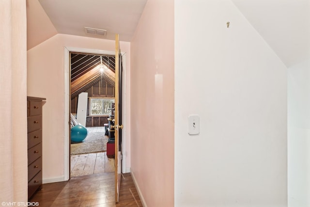 hallway featuring visible vents, baseboards, lofted ceiling, and hardwood / wood-style flooring