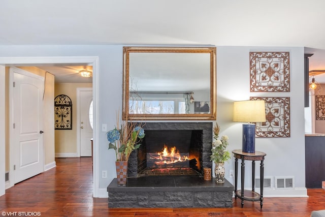 living area with wood finished floors, baseboards, and a lit fireplace