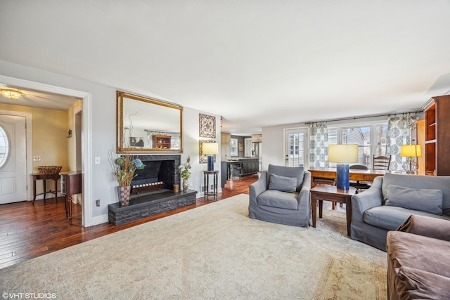 living room featuring hardwood / wood-style floors, a fireplace with raised hearth, and baseboards