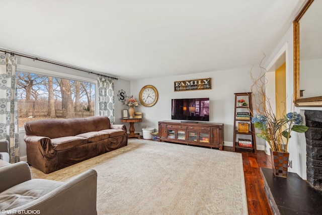 living area featuring dark wood-type flooring, a fireplace, and baseboards