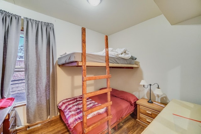 bedroom with wood-type flooring and vaulted ceiling