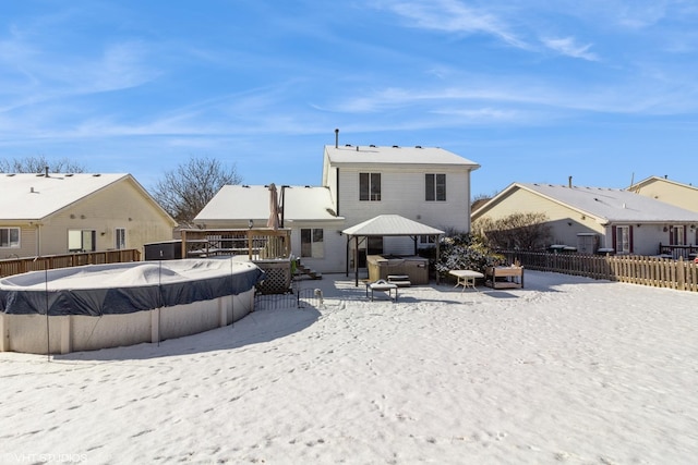 snow covered house with a pool with hot tub and a gazebo