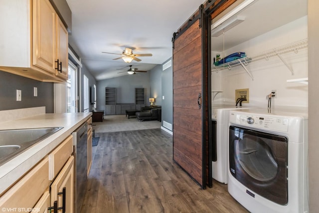 washroom featuring dark wood-type flooring, washing machine and dryer, a barn door, and ceiling fan