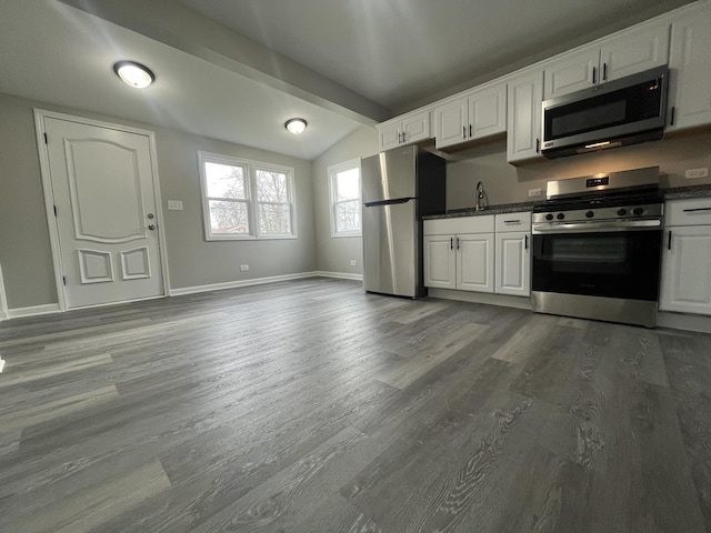 kitchen featuring wood-type flooring, lofted ceiling with beams, white cabinets, and appliances with stainless steel finishes