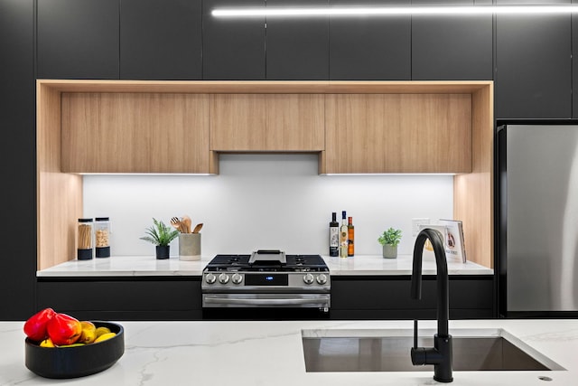 kitchen with light stone countertops, appliances with stainless steel finishes, and sink