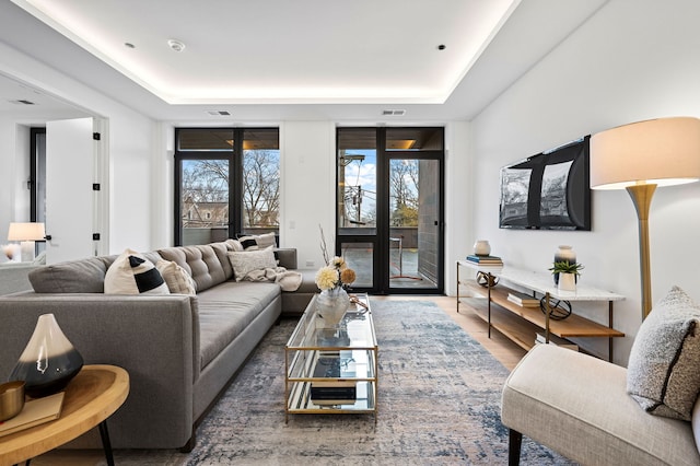 living room featuring hardwood / wood-style flooring and a tray ceiling