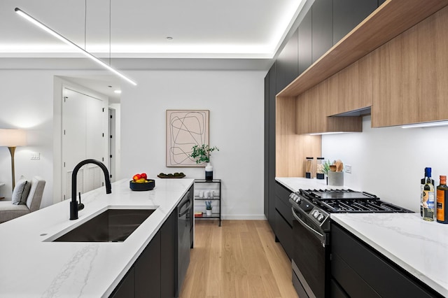 kitchen featuring pendant lighting, gas range oven, sink, and light stone countertops