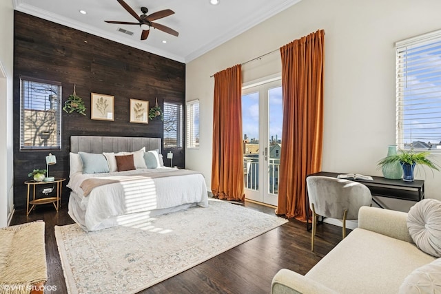 bedroom featuring an accent wall, dark wood-type flooring, access to exterior, crown molding, and multiple windows