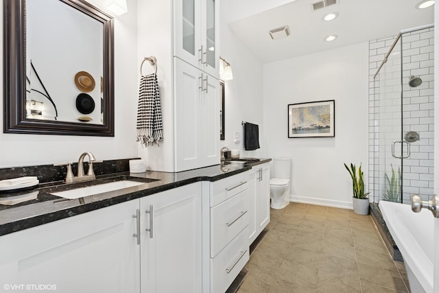 bathroom with double vanity, visible vents, toilet, a shower with shower door, and a sink