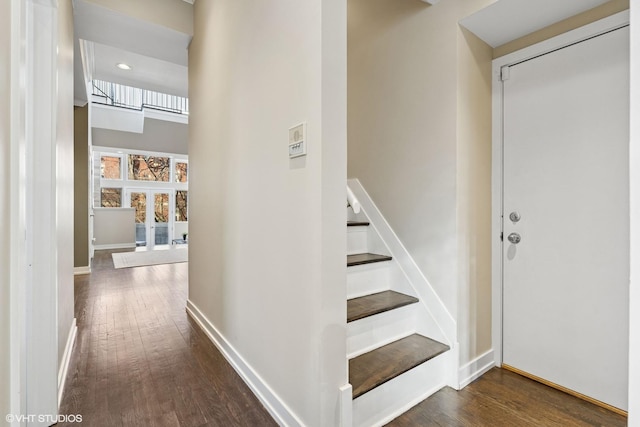 stairway with a high ceiling, baseboards, wood finished floors, and french doors