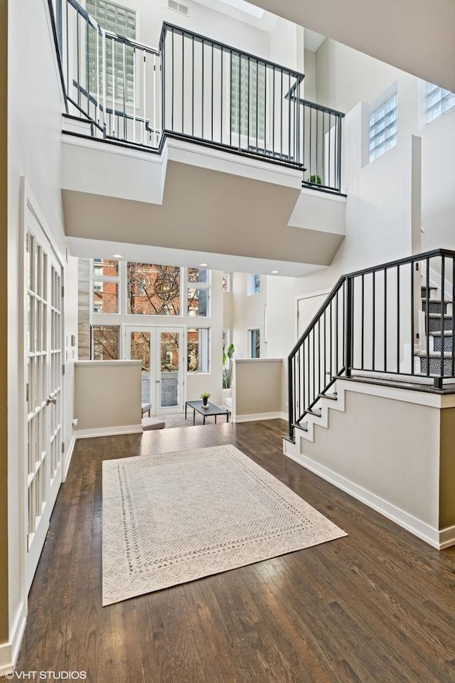 entryway with french doors, stairway, a towering ceiling, wood finished floors, and baseboards