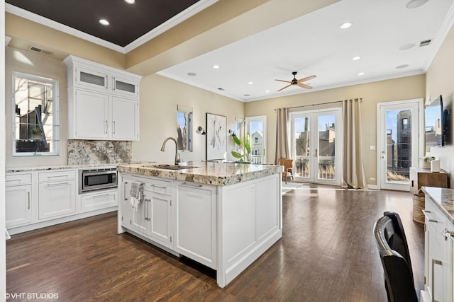 kitchen featuring dark wood-style floors, visible vents, stainless steel microwave, and a sink