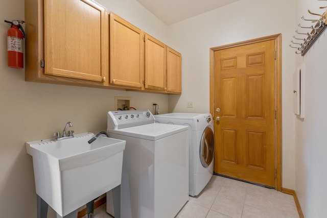 laundry room with light tile patterned floors, separate washer and dryer, a sink, baseboards, and cabinet space