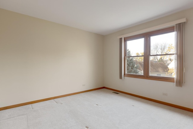 spare room featuring light colored carpet, visible vents, and baseboards