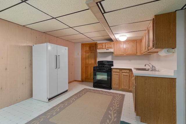 kitchen featuring light floors, freestanding refrigerator, black range with gas stovetop, light countertops, and under cabinet range hood