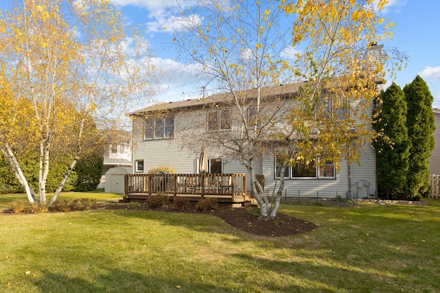 rear view of property featuring a deck, a storage shed, and a lawn