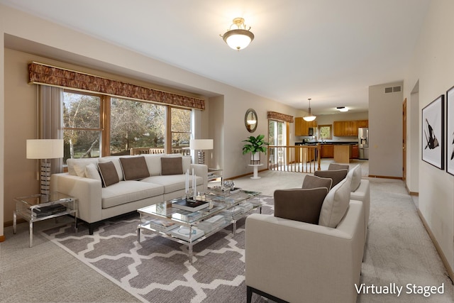 living area with light carpet, baseboards, and visible vents