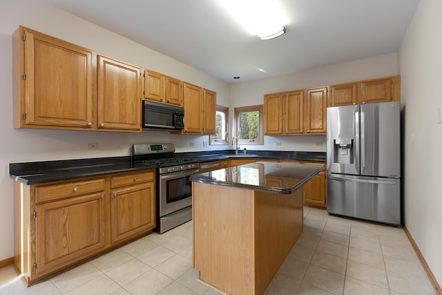 kitchen with light tile patterned floors, a kitchen island, appliances with stainless steel finishes, and a sink