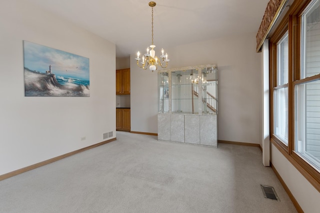 unfurnished dining area featuring an inviting chandelier, baseboards, visible vents, and light colored carpet