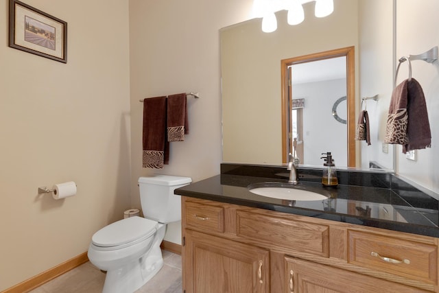 half bath with toilet, tile patterned floors, baseboards, and vanity