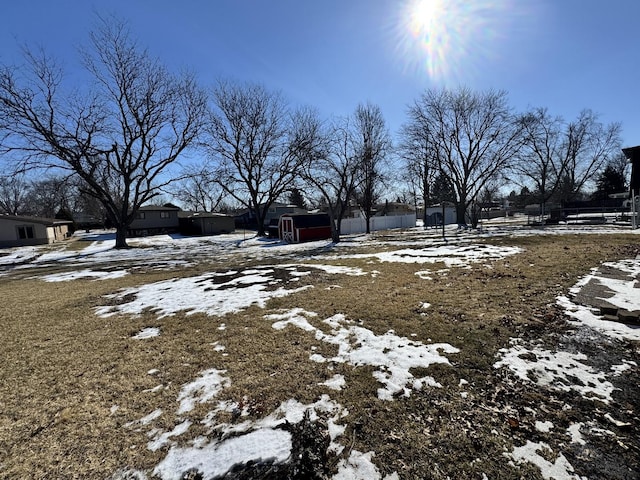 yard layered in snow with fence and a storage shed