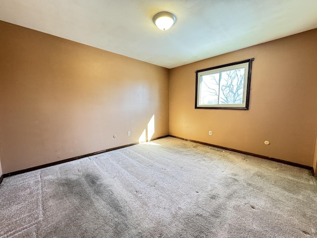 empty room with light colored carpet, visible vents, and baseboards