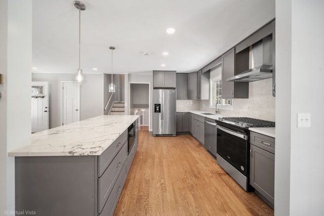 kitchen featuring stainless steel appliances, tasteful backsplash, gray cabinets, light wood-style floors, and a sink