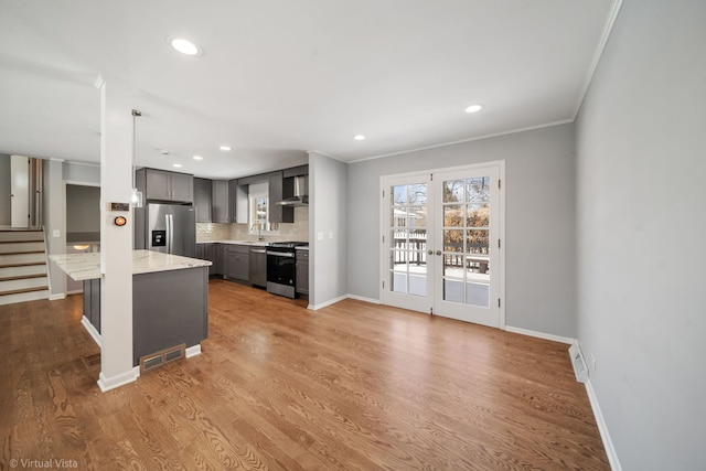 kitchen featuring appliances with stainless steel finishes, light stone counters, gray cabinetry, wall chimney range hood, and pendant lighting