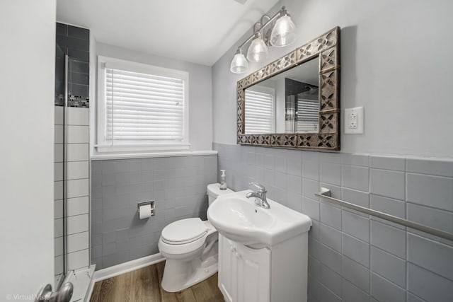 bathroom with a wainscoted wall, tile walls, toilet, vanity, and wood finished floors