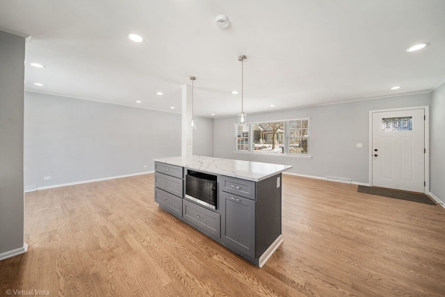 kitchen featuring light wood-type flooring, pendant lighting, gray cabinetry, and light stone countertops