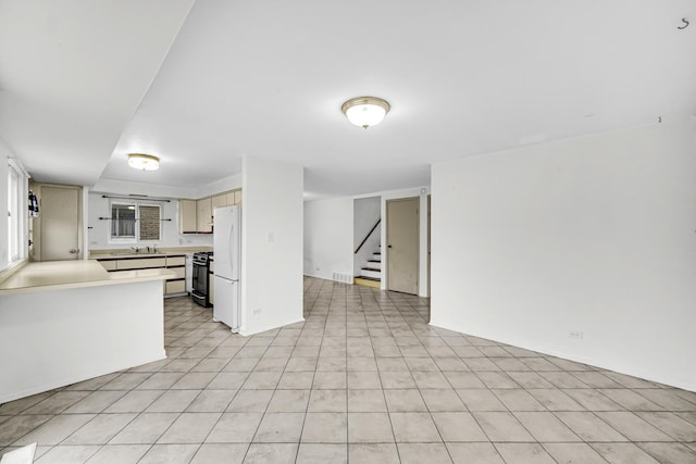 kitchen with white refrigerator, black gas stove, sink, and light tile patterned floors