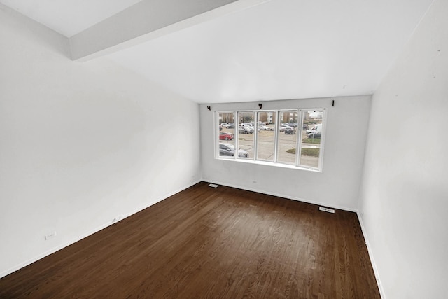 spare room with dark hardwood / wood-style floors and beam ceiling