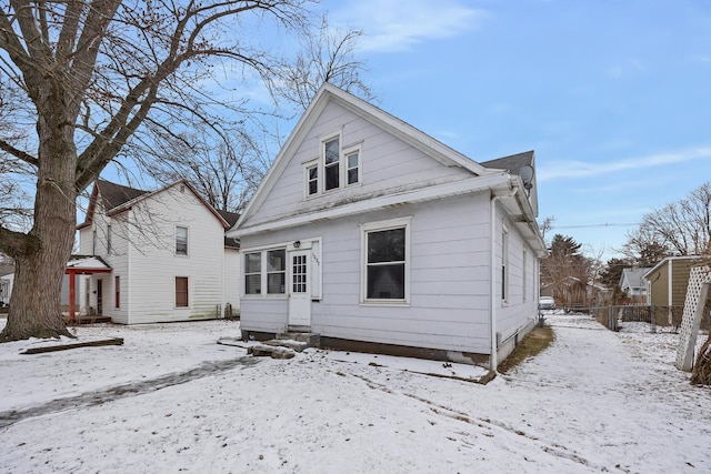 snow covered rear of property with entry steps and fence