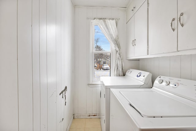 clothes washing area with light tile patterned floors, washing machine and clothes dryer, and cabinet space