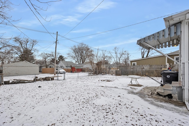 yard covered in snow featuring fence and a detached garage