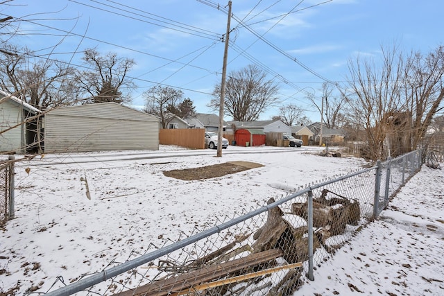 yard covered in snow featuring an outbuilding, fence, a residential view, and a storage unit