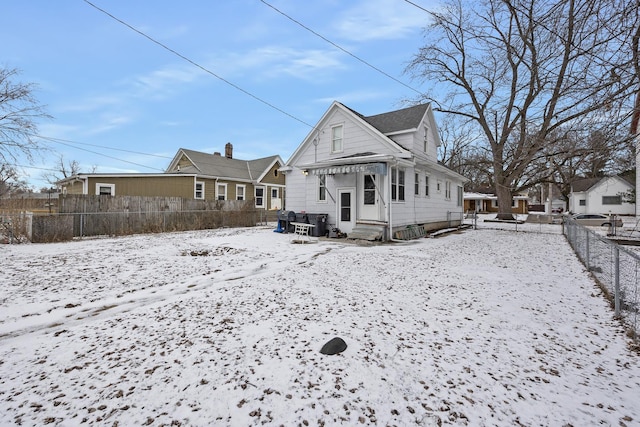 snow covered property with entry steps and fence