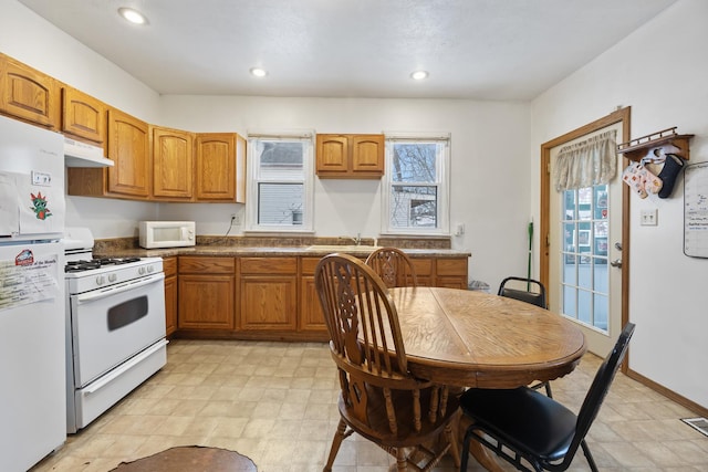 kitchen featuring white appliances, recessed lighting, brown cabinets, and under cabinet range hood