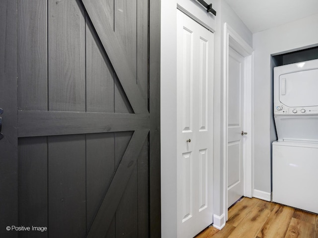 washroom with laundry area, stacked washer / dryer, and light wood-style flooring