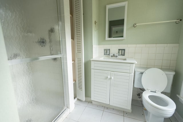 bathroom with tile walls, vanity, a shower with shower door, tile patterned floors, and toilet